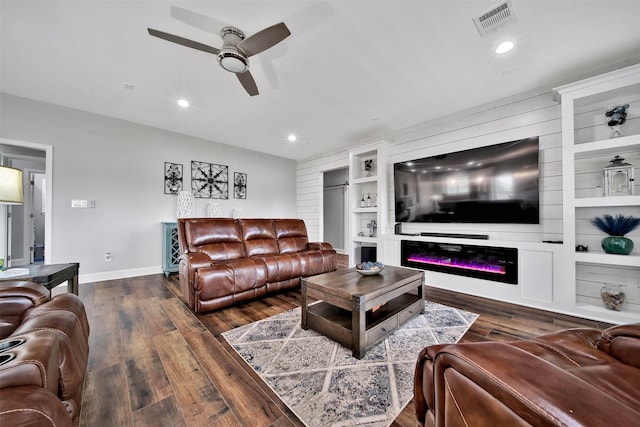 living room featuring built in shelves, ceiling fan, and dark hardwood / wood-style floors