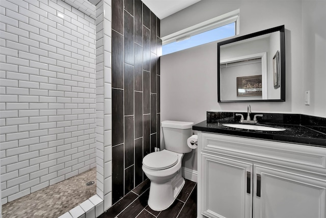 bathroom featuring oversized vanity, a tile shower, and toilet