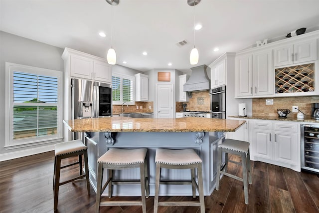 kitchen featuring premium range hood, pendant lighting, backsplash, and white cabinets