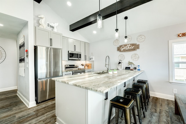 kitchen with appliances with stainless steel finishes, dark wood-type flooring, decorative light fixtures, and vaulted ceiling with beams