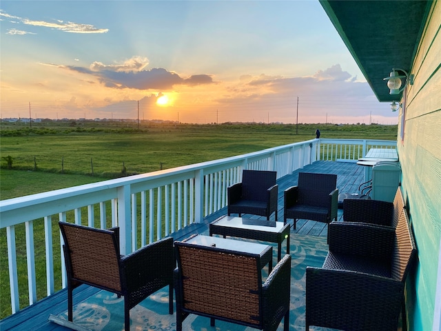 deck at dusk with a rural view, a lawn, and an outdoor living space