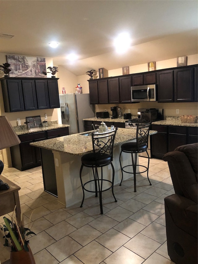 kitchen featuring a kitchen breakfast bar, stainless steel appliances, and an island with sink