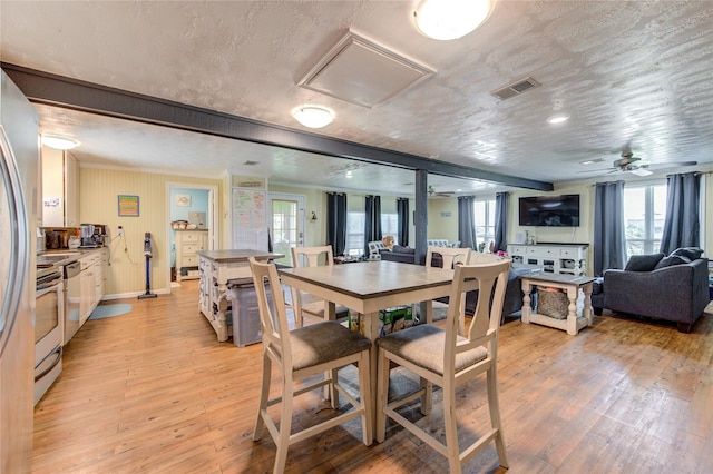 dining area with a textured ceiling, ceiling fan, and light hardwood / wood-style flooring