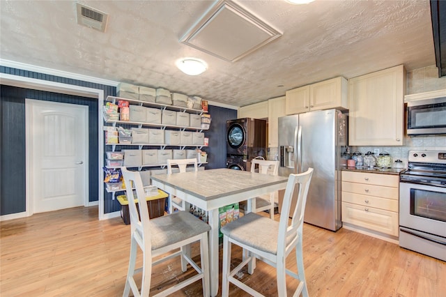 kitchen with a textured ceiling, stainless steel appliances, and light wood-type flooring