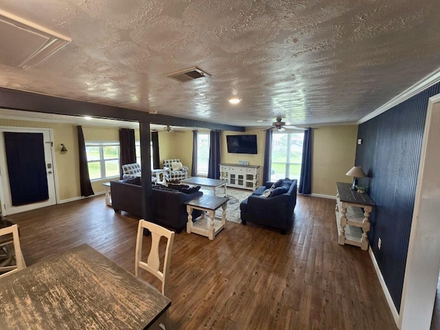 living room with ceiling fan, dark wood-type flooring, crown molding, and a healthy amount of sunlight