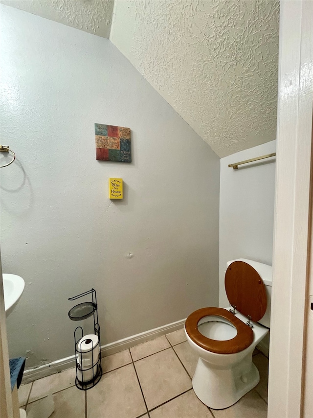 bathroom with lofted ceiling, a textured ceiling, tile patterned floors, and toilet