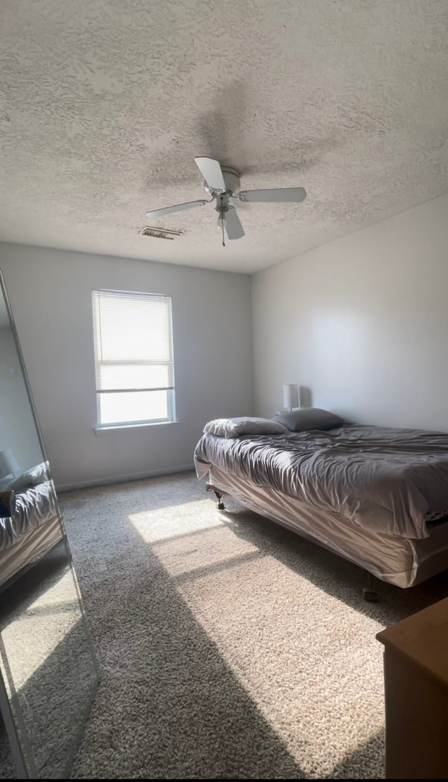 bedroom featuring ceiling fan, a textured ceiling, and carpet floors