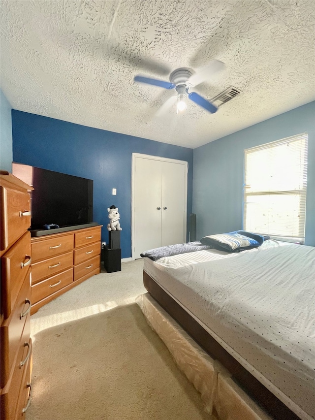 carpeted bedroom featuring a textured ceiling, a closet, and ceiling fan