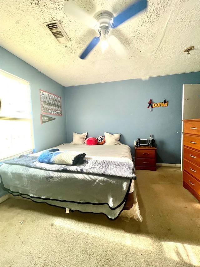 bedroom featuring ceiling fan, a textured ceiling, and light colored carpet