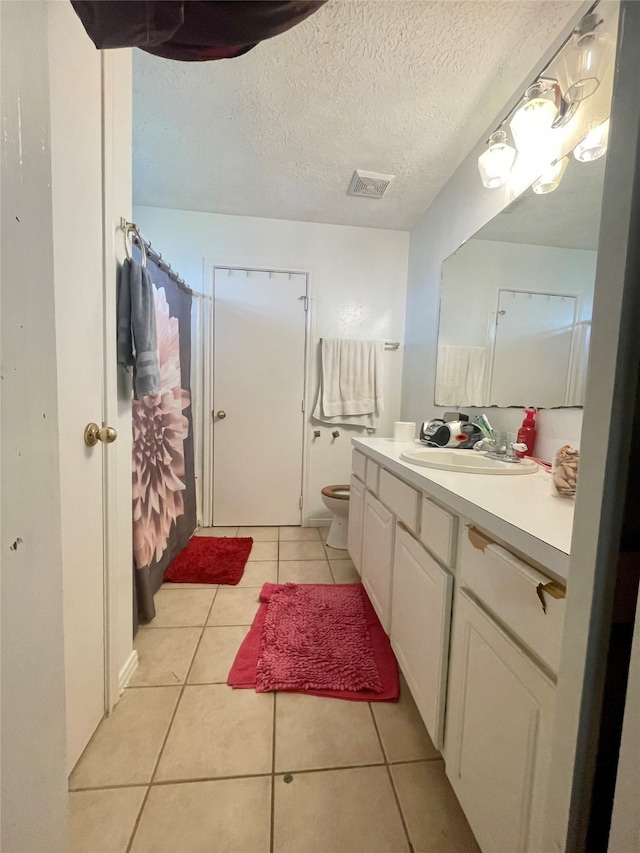 bathroom with vanity, a textured ceiling, toilet, and tile patterned flooring