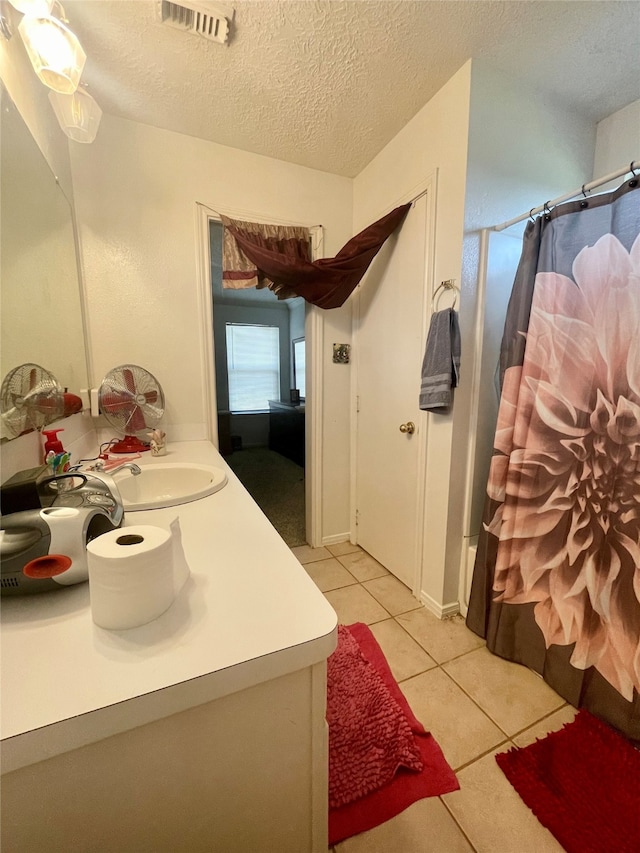 bathroom with a textured ceiling, vanity, and tile patterned flooring