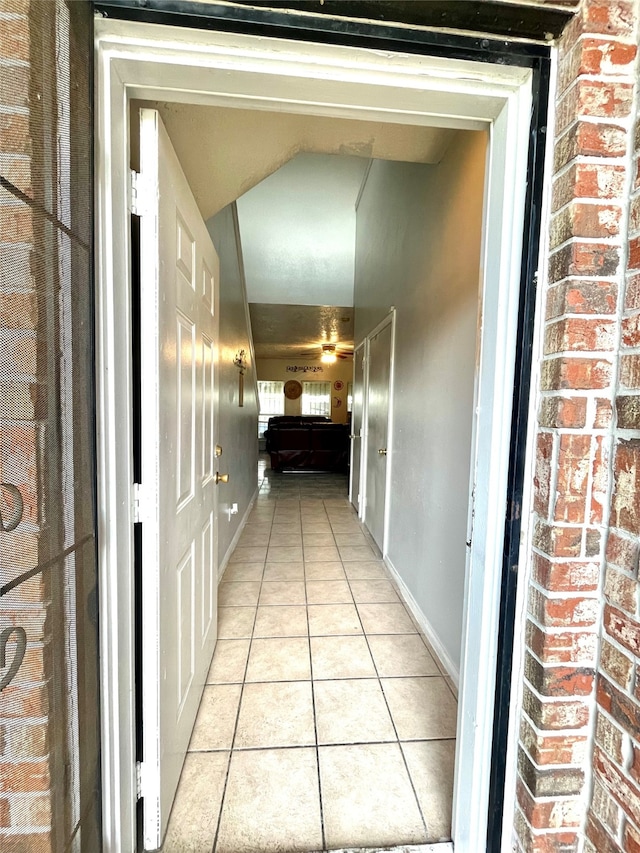 hallway with light tile patterned flooring and brick wall