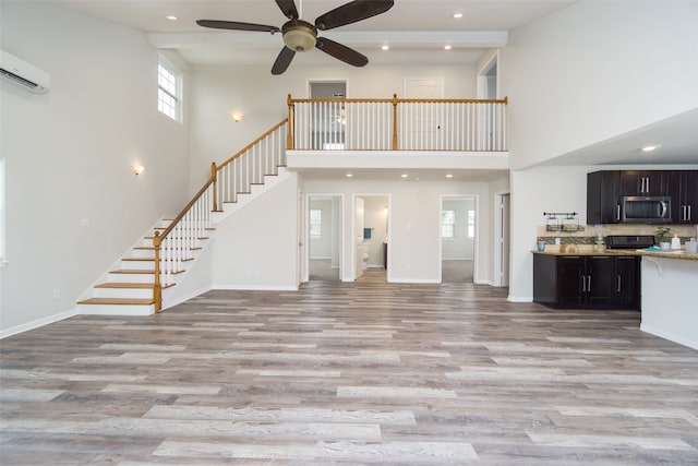 unfurnished living room featuring a wealth of natural light, ceiling fan, and light wood-type flooring