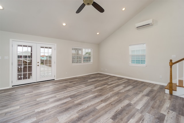 empty room with high vaulted ceiling, wood-type flooring, and a wall mounted AC