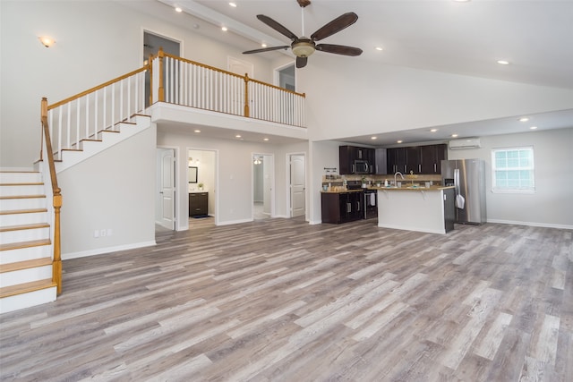 unfurnished living room with light hardwood / wood-style flooring, high vaulted ceiling, ceiling fan, and sink