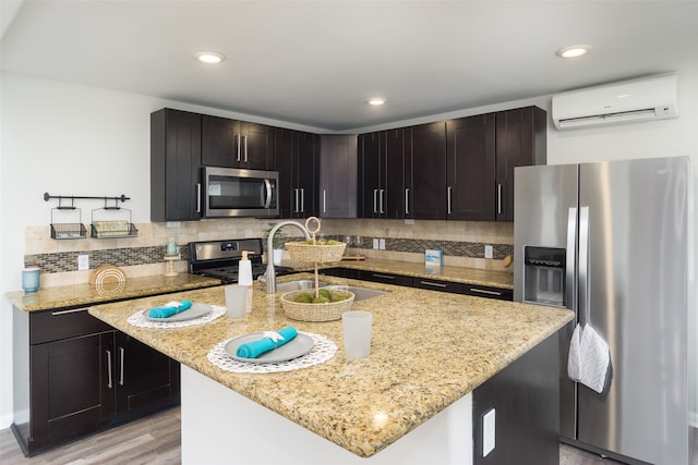 kitchen with a center island with sink, tasteful backsplash, stainless steel appliances, and a wall unit AC