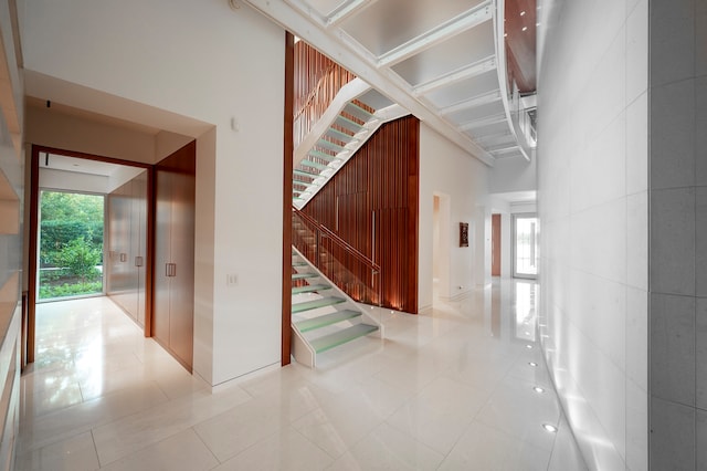 corridor featuring light tile floors and a towering ceiling