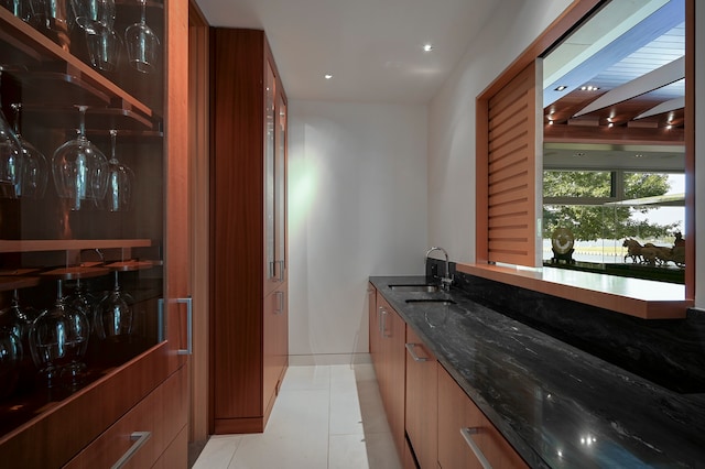 kitchen featuring sink, dark stone counters, and light tile floors