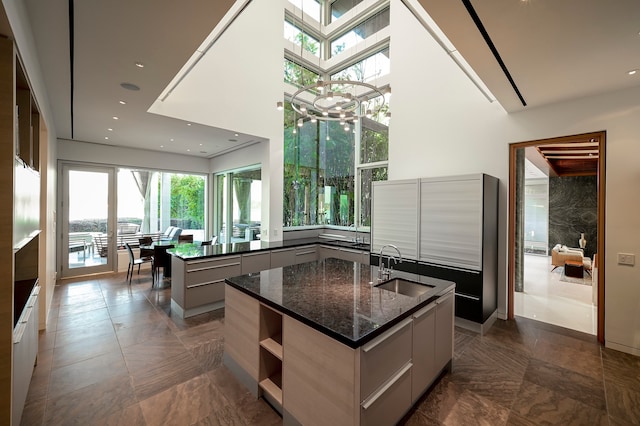 kitchen featuring a wealth of natural light, sink, dark tile flooring, and a kitchen island with sink