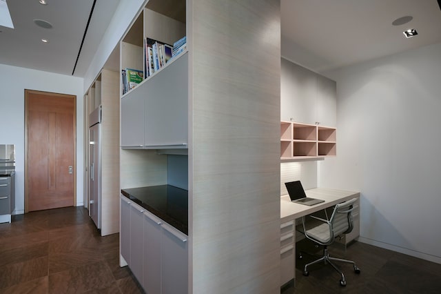 unfurnished office featuring built in desk and dark parquet floors