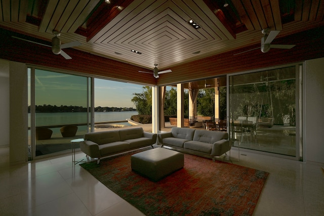 tiled living room featuring wooden ceiling, a water view, ceiling fan, and a wall of windows