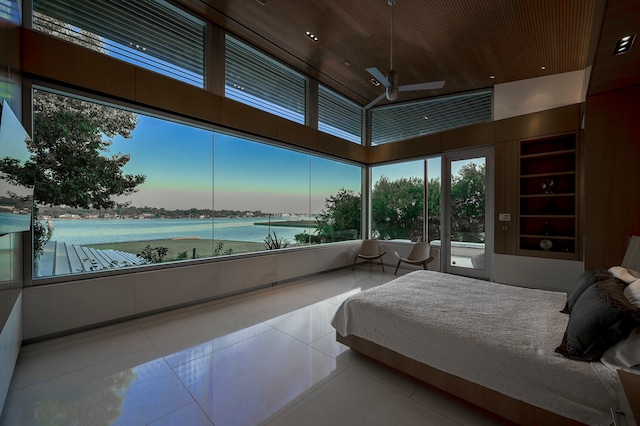 bedroom featuring a water view, light tile floors, and a towering ceiling