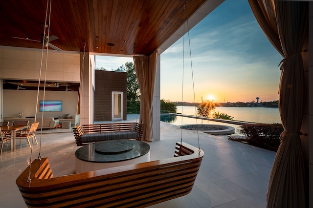 patio terrace at dusk featuring a water view