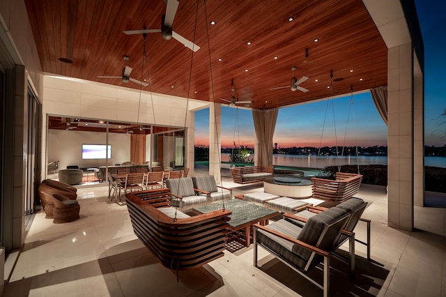 patio terrace at dusk with a water view, ceiling fan, and an outdoor hangout area