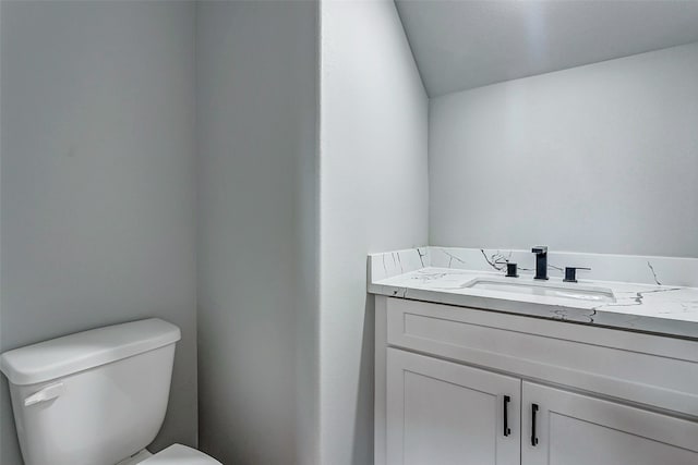 bathroom featuring lofted ceiling, vanity, and toilet