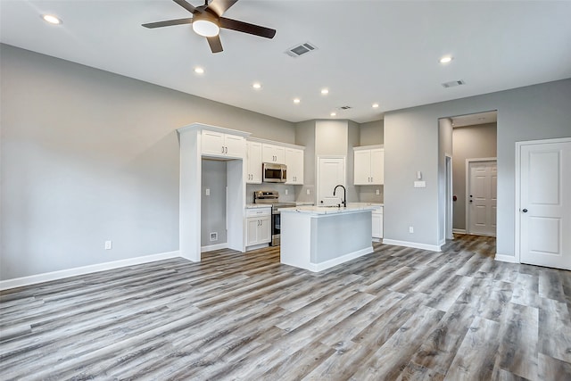 kitchen featuring a center island with sink, light hardwood / wood-style flooring, stainless steel appliances, white cabinetry, and ceiling fan