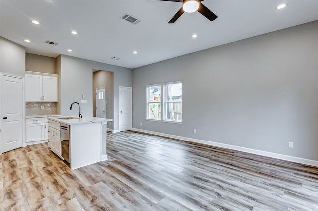 kitchen with a center island with sink, sink, white cabinetry, ceiling fan, and light wood-type flooring