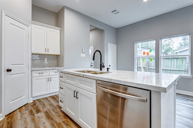 kitchen featuring light hardwood / wood-style floors, white cabinetry, sink, an island with sink, and stainless steel dishwasher