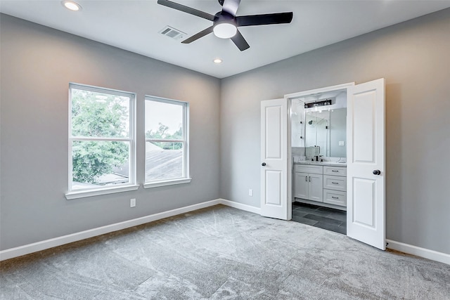 unfurnished bedroom featuring ceiling fan, dark colored carpet, and connected bathroom