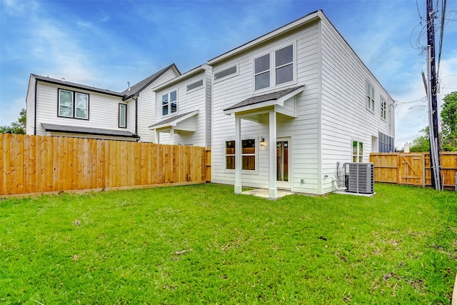 rear view of property with a yard and central air condition unit