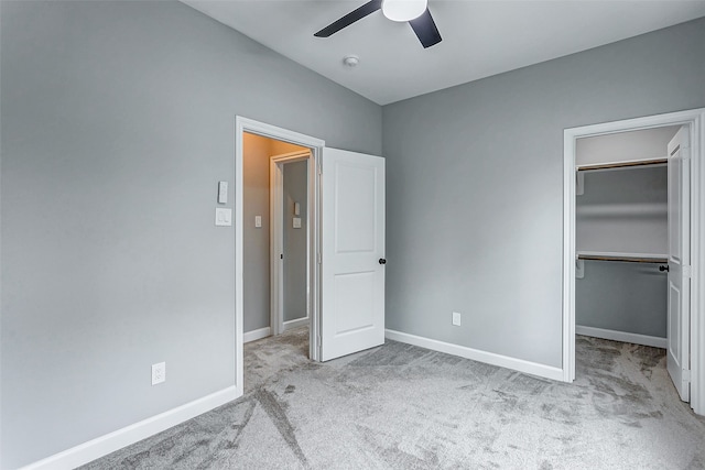 unfurnished bedroom with light colored carpet, a spacious closet, and ceiling fan