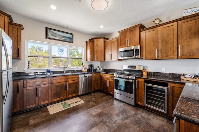 kitchen featuring dark tile patterned floors, wine cooler, dark stone counters, stainless steel appliances, and sink