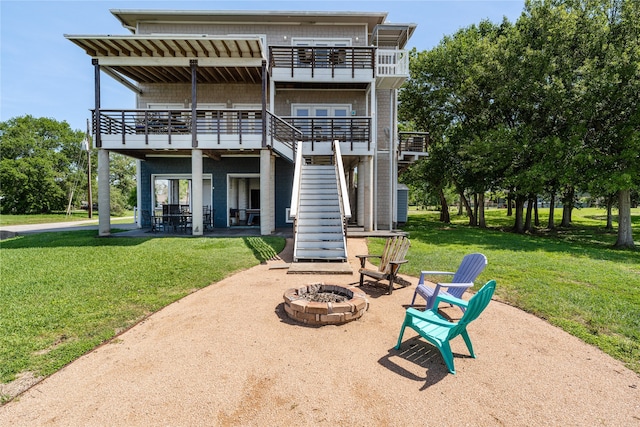 rear view of property featuring a deck, a patio, a lawn, and a fire pit