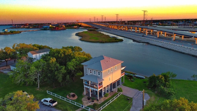 aerial view at dusk featuring a water view