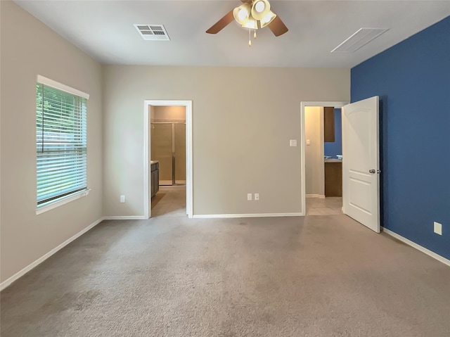 unfurnished bedroom with a closet, ceiling fan, light carpet, and a walk in closet