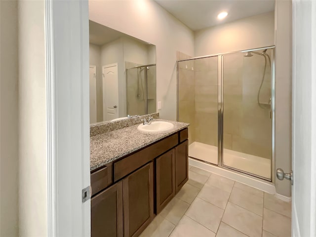 bathroom featuring a shower with shower door, tile flooring, and vanity