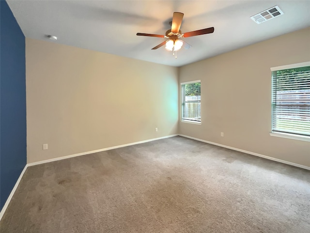 spare room featuring a healthy amount of sunlight, dark colored carpet, and ceiling fan