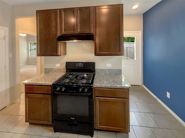 kitchen with black range with gas cooktop, light tile floors, and light stone countertops