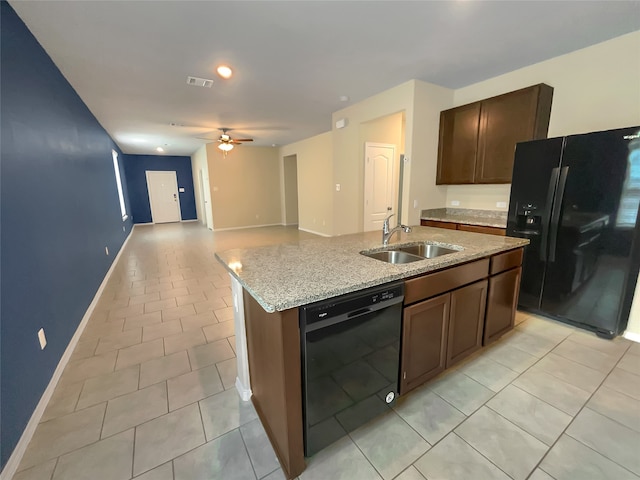 kitchen featuring ceiling fan, sink, black appliances, a center island with sink, and light stone countertops