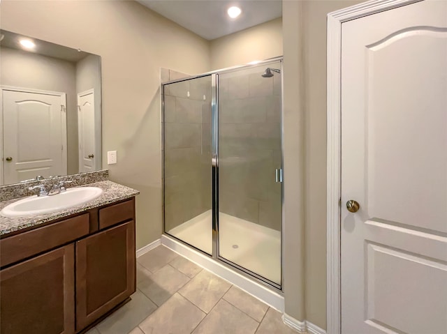 bathroom with a shower with shower door, oversized vanity, and tile floors