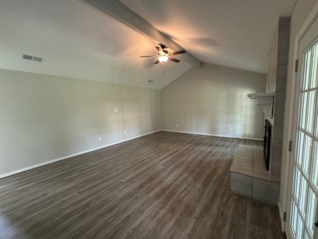 unfurnished room with ceiling fan, a tile fireplace, vaulted ceiling with beams, and dark hardwood / wood-style flooring