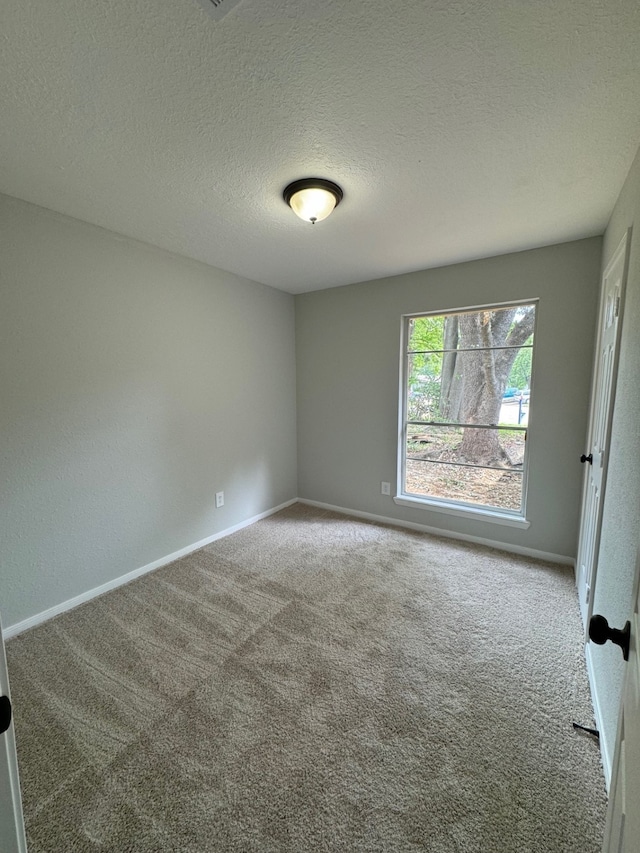 carpeted empty room featuring a textured ceiling