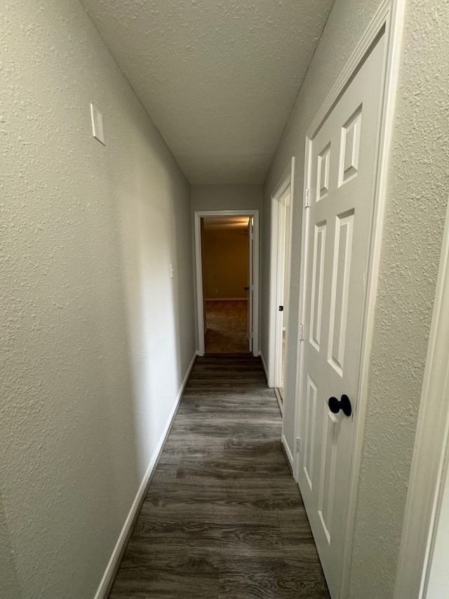 hall featuring a textured ceiling and dark wood-type flooring