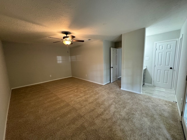 carpeted empty room featuring ceiling fan and a textured ceiling