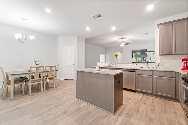 kitchen with appliances with stainless steel finishes, backsplash, light stone countertops, and light wood-type flooring