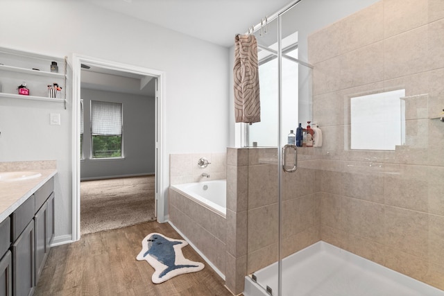 bathroom featuring plus walk in shower, vanity, and hardwood / wood-style flooring